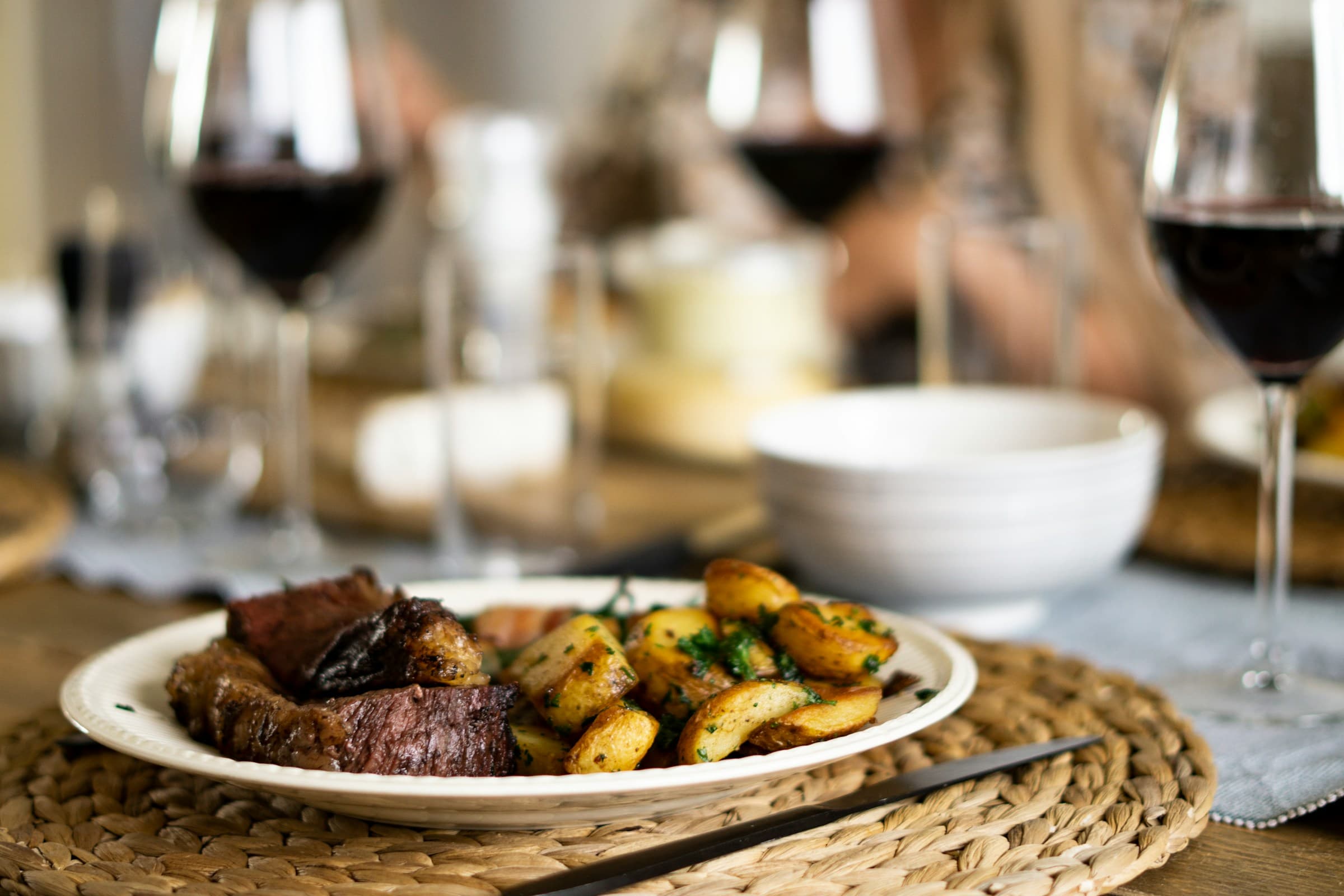 Plato de carne con papas y copas de vino tinto